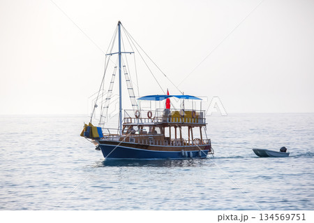 Traditional wooden boat sailing on calm waters near Turkey's coastline during sunrise Traditional wooden boat sailing on calm waters near Turkey's coastline during sunrise 134569751