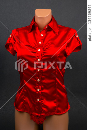 Vibrant red satin shirt with short sleeves displayed on a mannequin in a studio setting Vibrant red satin shirt with short sleeves displayed on a mannequin in a studio setting 134569842