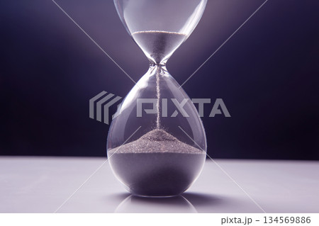 Elegant hourglass captures passage of time against a dark backdrop in soft lighting 134569886