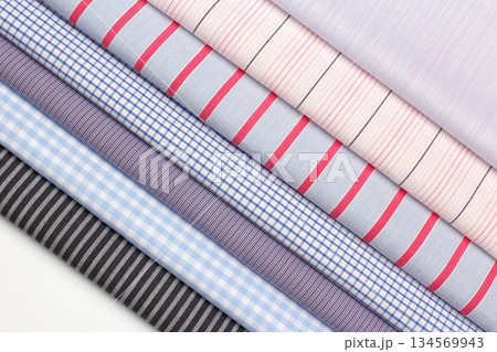 Different styles of folded cotton shirts displayed on a white surface Different styles of folded cotton shirts displayed on a white surface 134569943