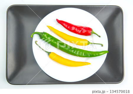 Colorful variety of chili peppers on a white plate with a black tray background 134570018