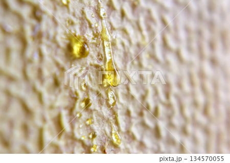 Bright yellow resin drips down textured surface in natural light setting 134570055