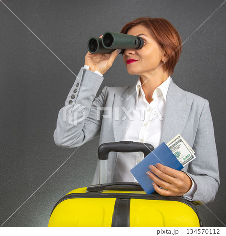 Business traveler using binoculars to spot her flight at the airport Business traveler using binoculars to spot her flight at the airport 134570112
