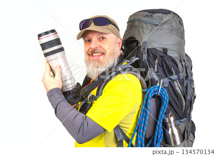 Outdoor enthusiast holds camera gear and prepares for adventure in bright yellow shirt 134570134