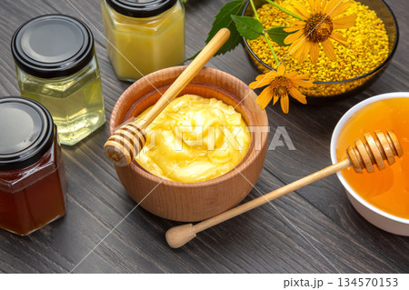 Honey and natural ingredients arranged on a wooden table with jars and a honey dipper Honey and natural ingredients arranged on a wooden table with jars and a honey dipper 134570153