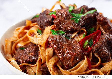 Udon noodles with Mongolian beef, green onions and vegetables, in a white plate, on a light background, homemade, no people, Udon noodles with Mongolian beef, green onions and vegetables, in a white plate, on a light background, homemade, no people, 134570982