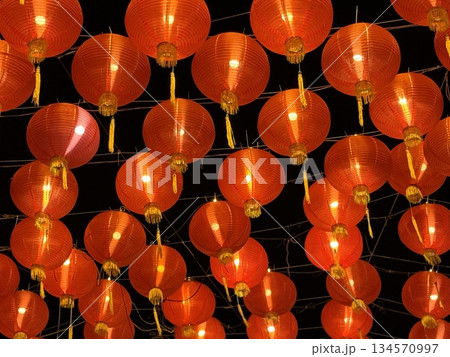 Vibrant red Chinese lanterns glow against a dark night, creating a warm, festive atmosphere perfect for celebrations, festivals, and cultural events. Ideal for mood setting, decoration, and seasonal 134570997