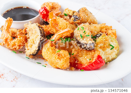 Shrimp and vegetable tempura, served with dipping sauce, on a white plate Shrimp and vegetable tempura, served with dipping sauce, on a white plate 134571046