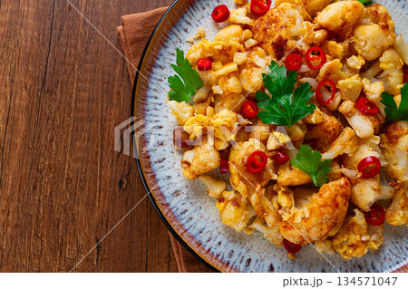 spicy fried cauliflower served on a wooden countertop, 134571047