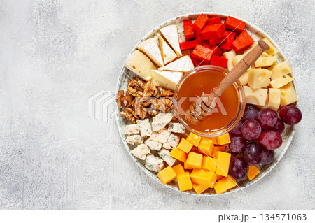 Appetizer, assorted cheese, with nuts and honey, on a round plate, top view, no people, Appetizer, assorted cheese, with nuts and honey, on a round plate, top view, no people, 134571063