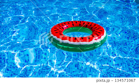 A bright ring-a float, with a watermelon, in the clear blue water of the pool, under the sunlight 134571067