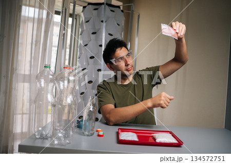 Agronomist wearing safety glasses examining fertilizer packet while preparing nutrient solution for vertical hydroponic system, highlighting innovative urban farming techniques. Agronomist wearing safety glasses examining fertilizer packet while preparing nutrient solution for vertical hydroponic system, highlighting innovative urban farming techniques. 134572751