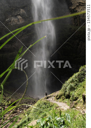 Hiker standing at base of Gocta Falls, highlighting dramatic scale, Peru Hiker standing at base of Gocta Falls, highlighting dramatic scale, Peru 134573511