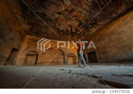 Tourist admiring colorful sandstone ceiling inside Royal Tomb, Petra, Jordan 134573520