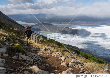 Hiker traversing steep trail overlooking Glacier Grey and Lago Grey, Chile 134573526