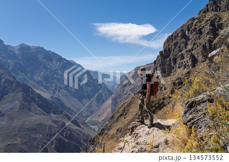 Hiker standing on narrow trail overlooking vast Colca Canyon, Peru Hiker standing on narrow trail overlooking vast Colca Canyon, Peru 134573552
