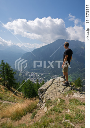 Hiker standing on cliff edge viewing Courmayeur town, Italian Alps 134573555