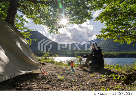 Hiker wild camping at Lago Escondido watching sunburst sunrise, Argentina 134573558