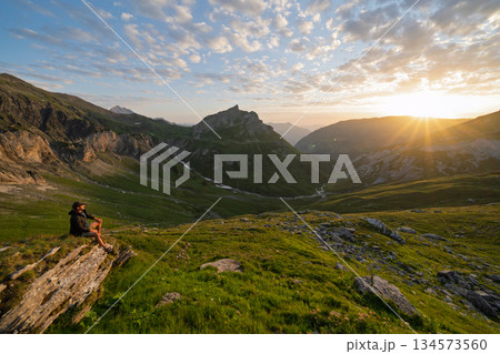 Hiker watching sunset over La Gittaz valley in French Alps, Tour du Mont Blanc 134573560