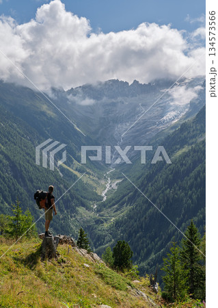 Hiker standing on cliff edge viewing Trient Glacier valley, Swiss Alps, TMB 134573566