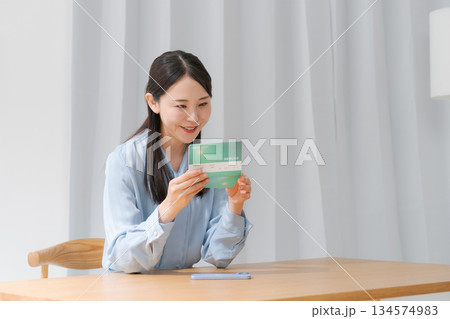 通帳を見て微笑む女性 134574983