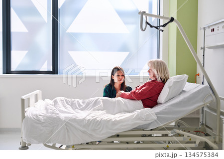 Caring interaction between a nurse and a patient in a hospital room during daytime Caring interaction between a nurse and a patient in a hospital room during daytime 134575384