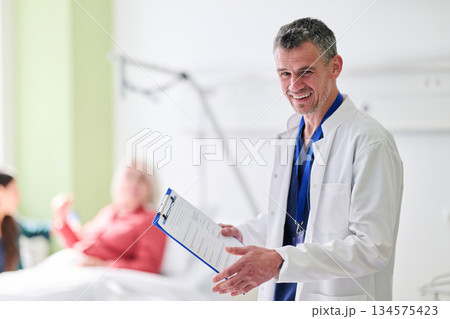 Smiling doctor interacts with patients in a bright hospital room during a morning shift 134575423