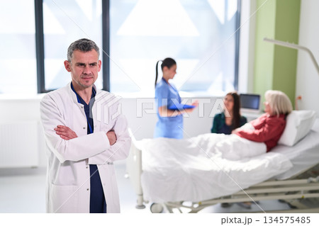 Doctor oversees patient care in hospital with nurses providing assistance and support during treatment process 134575485