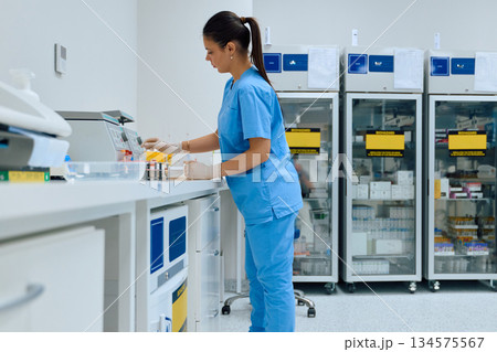 Medical lab technician prepares samples in a laboratory with storage units and equipment present Medical lab technician prepares samples in a laboratory with storage units and equipment present 134575567