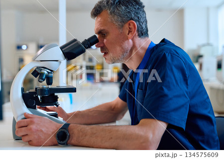 Scientist examines samples through microscope in a laboratory setting during daytime Scientist examines samples through microscope in a laboratory setting during daytime 134575609