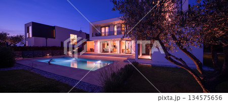 Modern luxury villa with a luminous swimming pool at twilight. Contemporary architecture, sleek design, and inviting interior lights create a serene and elegant evening ambiance, ideal for upscale Modern luxury villa with a luminous swimming pool at twilight. Contemporary architecture, sleek design, and inviting interior lights create a serene and elegant evening ambiance, ideal for upscale 134575656