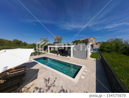Aerial view of a modern modular house with flat roof, swimming pool, and patio. Contemporary prefabricated home architecture featuring sustainable design and outdoor living space 134575670