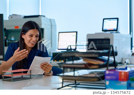 Healthcare professional reviews patient documents at a modern office in morning sunlight 134575672