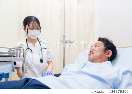 病棟で入院患者のケアをする医療従事者の女性 病棟で入院患者のケアをする医療従事者の女性 134576303