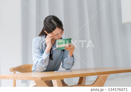 通帳を見て困る女性 通帳を見て困る女性 134576871