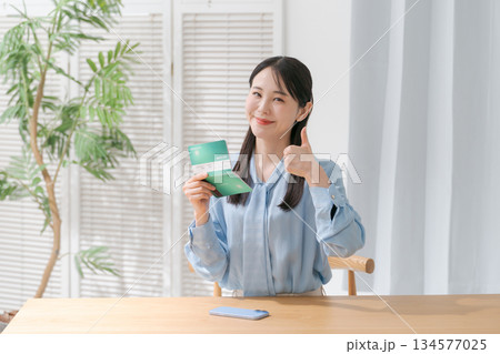 通帳を見て微笑む女性 134577025