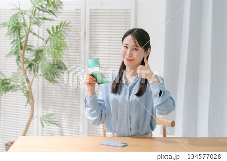 通帳を見て微笑む女性 134577028