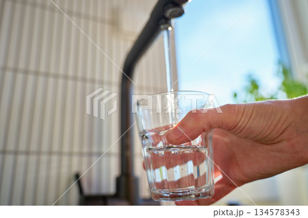 Glass filled with clear water from black kitchen faucet in daylight Glass filled with clear water from black kitchen faucet in daylight 134578343