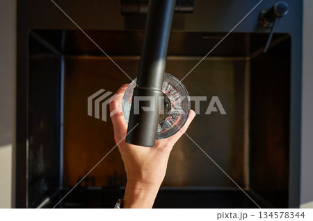 Top view of hand filling glass with drinking water under kitchen faucet in sink 134578344