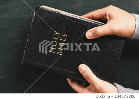 Hands in prayer above Holy Bible on wooden table, symbolizing Christian faith, worship, devotion, trust in God, spiritual religious background with copy space for church, prayer, meditation concepts. Hands in prayer above Holy Bible on wooden table, symbolizing Christian faith, worship, devotion, trust in God, spiritual religious background with copy space for church, prayer, meditation concepts. 134578806