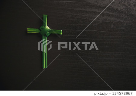 Palm leaf cross attached to crown of thorns green palm leaves on dark background symbolizing Christian faith Palm Sunday sacrifice Easter reflection religious concept for worship prayer church design 134578967