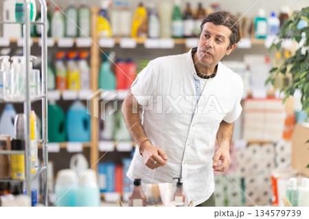 Man walks through household store, studies windows, looks at assortment of goods, looking for something 134579739