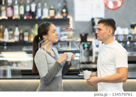 Young couple talking and drinking coffee in cafe Young couple talking and drinking coffee in cafe 134579761