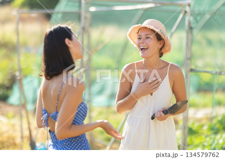 Two women talking in garden greenhouse Two women talking in garden greenhouse 134579762