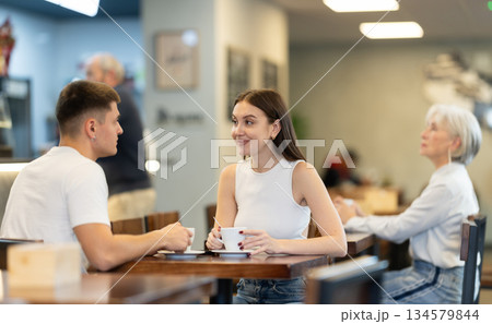 Young couple talking over a cup of coffee in a cozy cafe Young couple talking over a cup of coffee in a cozy cafe 134579844