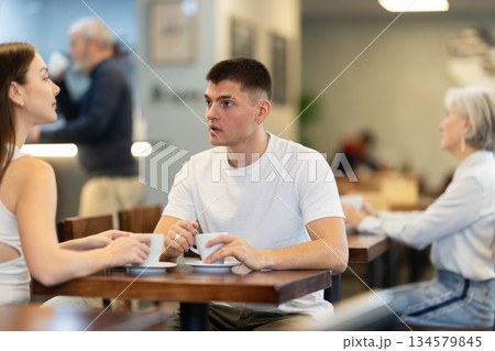 Couple man and woman drinking coffee and talking in cafe Couple man and woman drinking coffee and talking in cafe 134579845