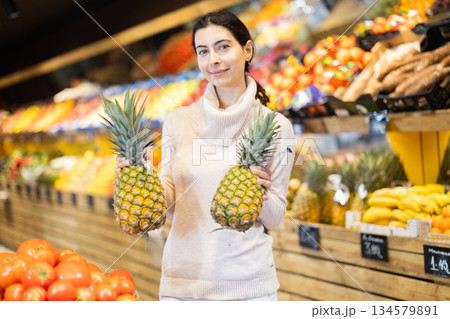 In vegetable store, young woman customer buy pineapple 134579891