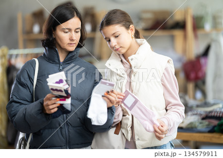 Mother and teen daughter looks at products in store and selects cotton socks. 134579911