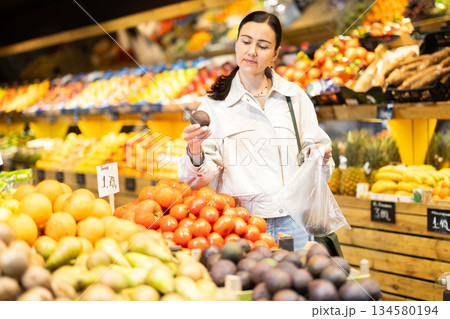 Woman shopping in grocery supermarket - choosing ripe passion fruit 134580194