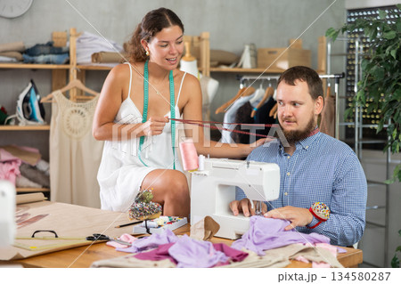 Young female dressmaker working with mannequin while other sews 134580287